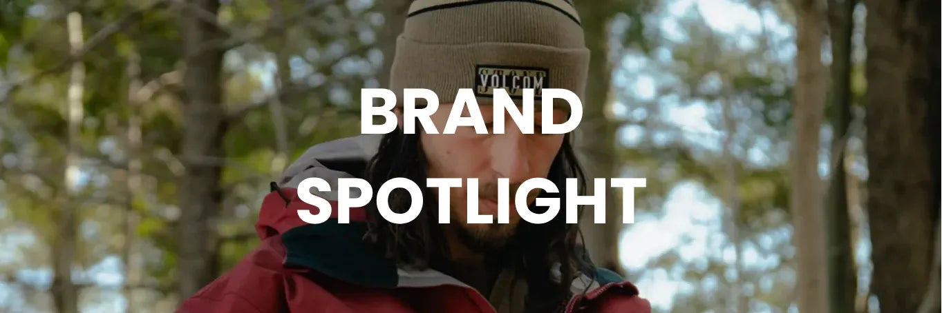 Person wearing a red jacket and tan beanie with a brand logo in a forest setting, text overlay 'BRAND SPOTLIGHT'.