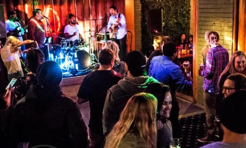 Live band performing on stage with an audience at a bar.