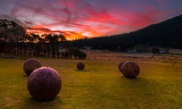 Boulders on a grassy field with a colorful sunset sky