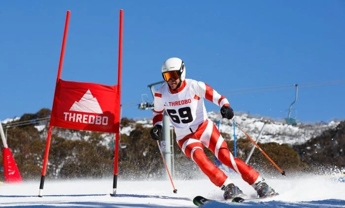 Ski racer in action with Thredbo branding on a snowy course