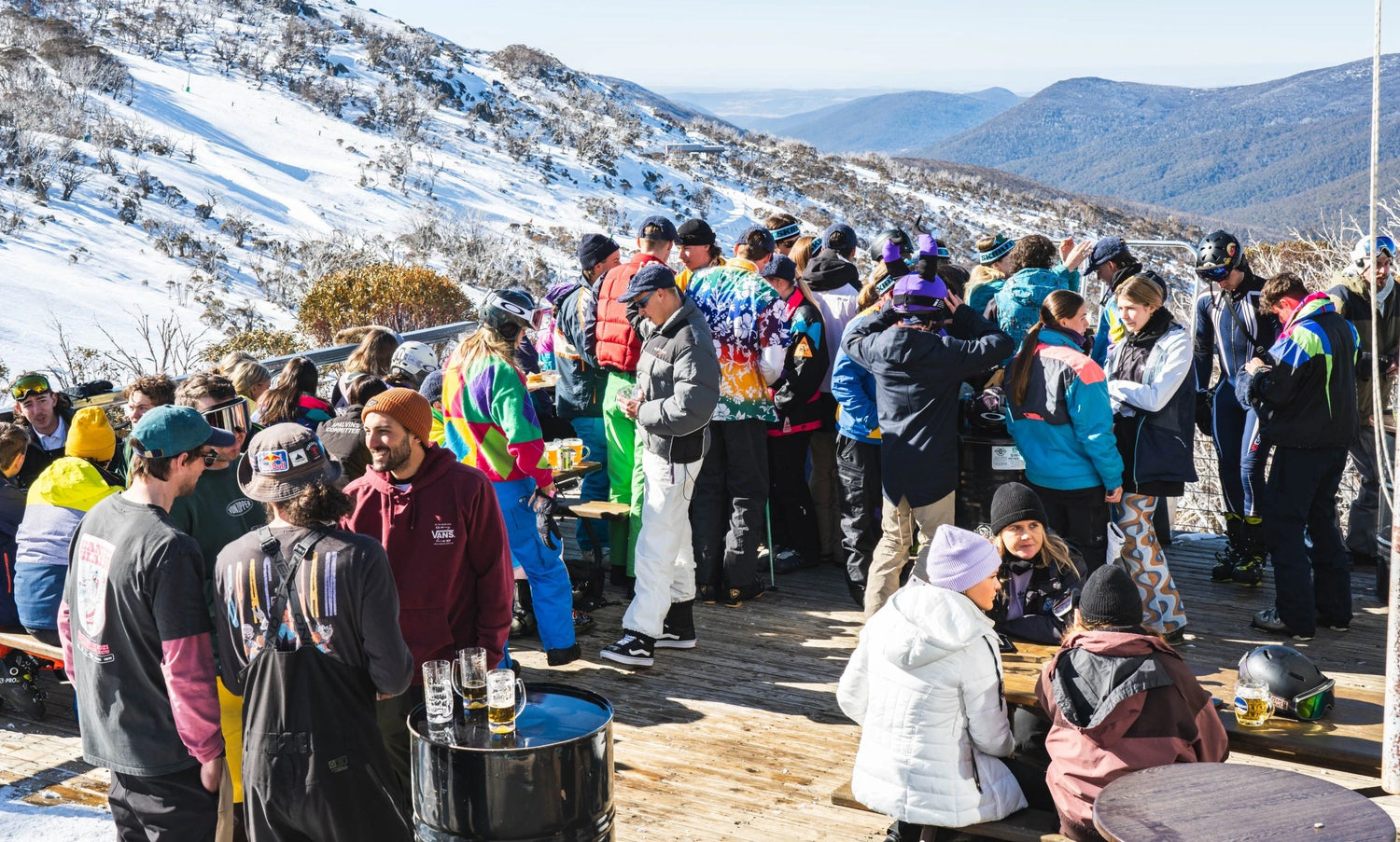 Group of people gathered outdoors in a snowy mountainous area, likely at a ski resort.